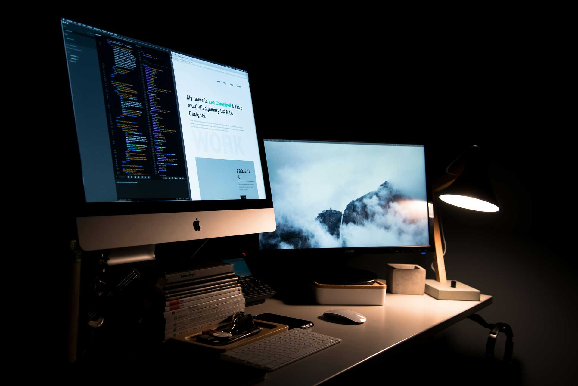 A silver iMac with a second monitor turned in a dark room