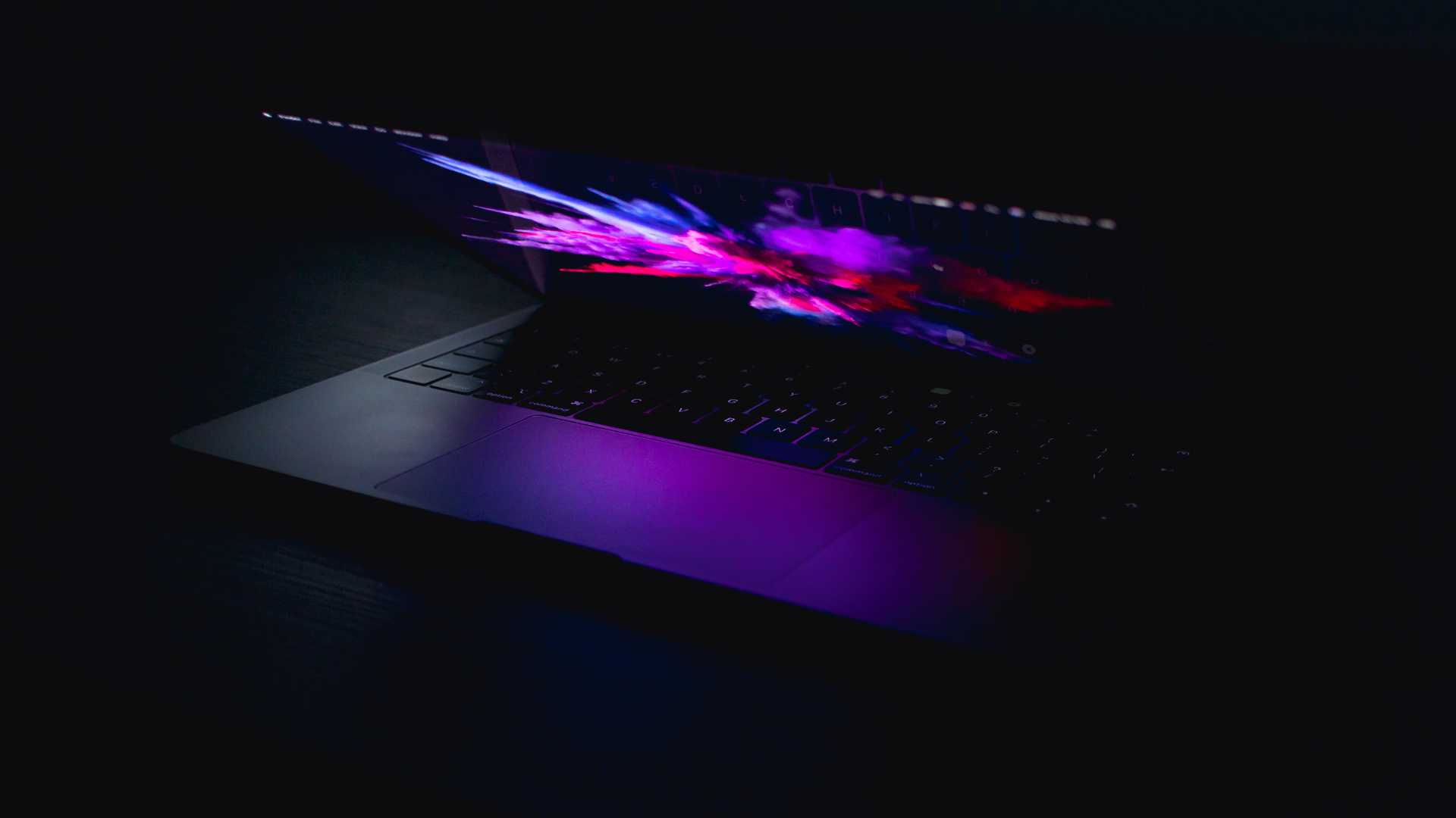 A laptop partially opened on with an explosion of colors coming from the screen